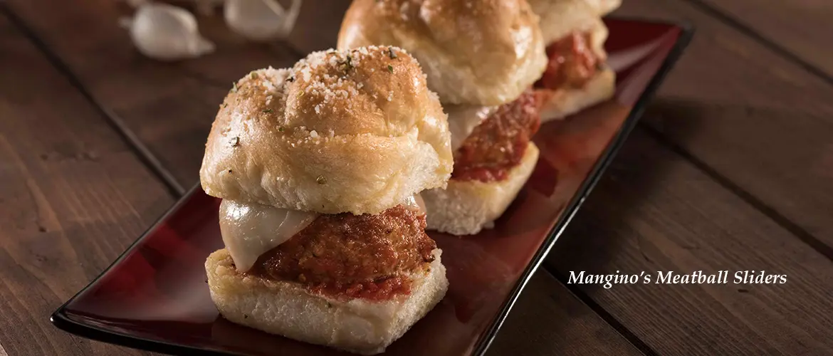 A plate of meatball sliders topped with melted cheese and marinara sauce, served on a dark rectangular dish. Text reads "Mangino's Meatball Sliders.