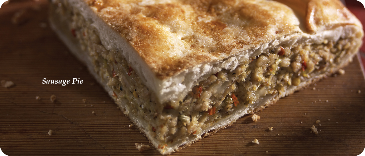 Close-up of a sliced sausage pie with a golden-brown crust, showing a filling made of minced sausage and spices.