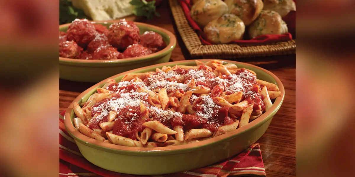 A bowl of pasta covered in sauce and parmesan cheese.