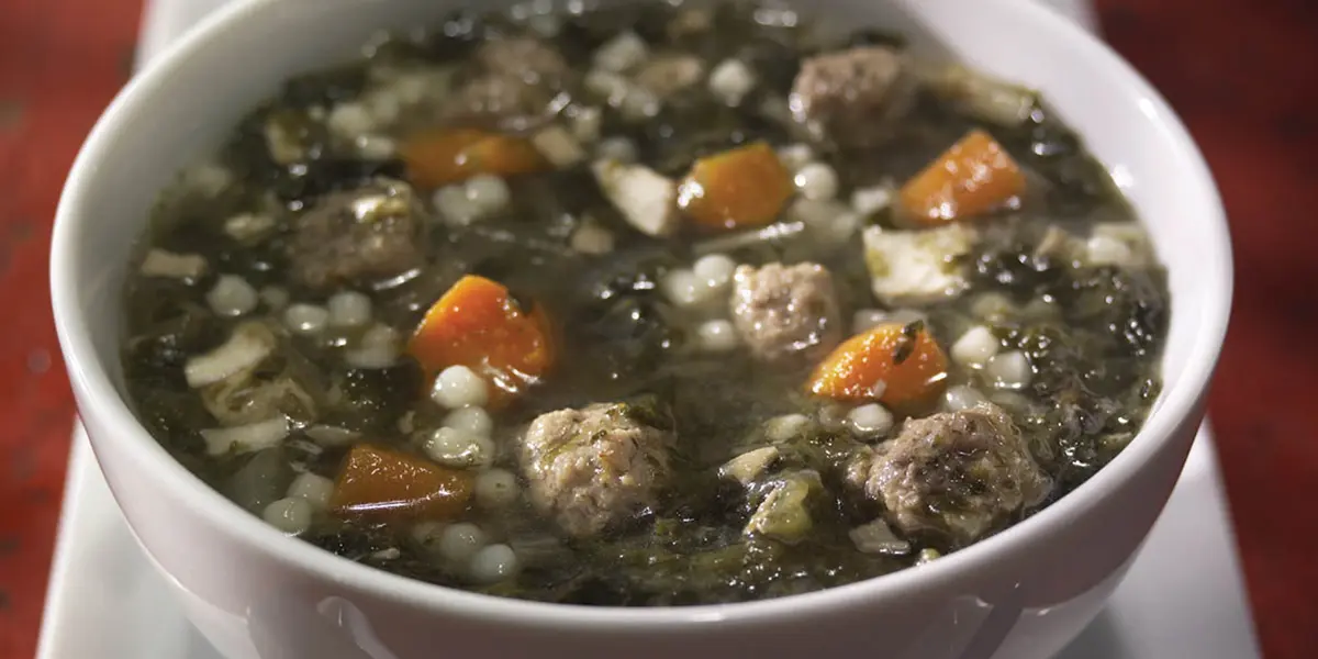 A bowl of soup with meatballs and vegetables.