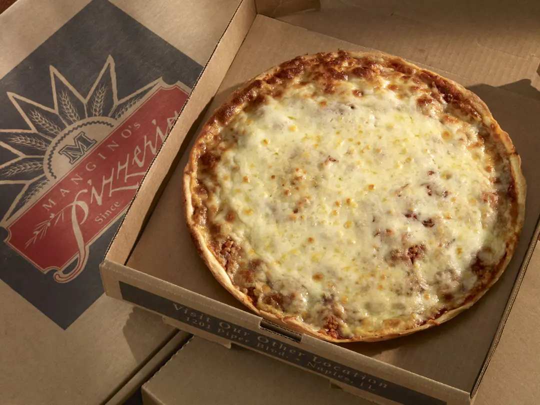 A pizza sitting in a box on top of the floor.