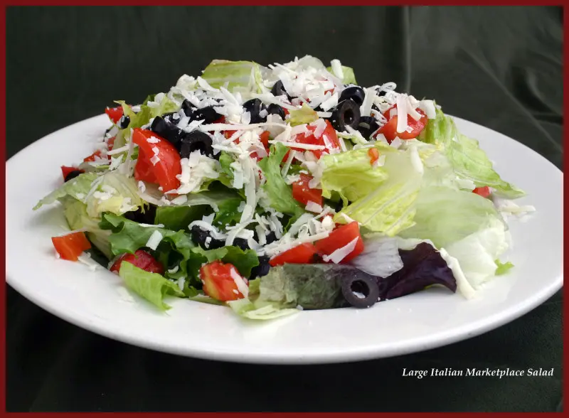 A plate of salad with tomatoes, lettuce and cheese.