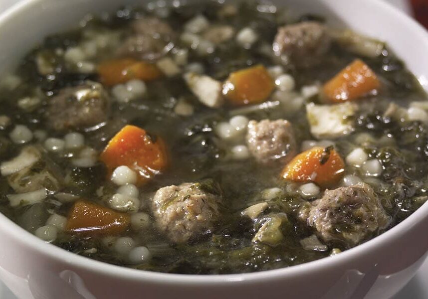 A bowl of soup with meatballs and vegetables.