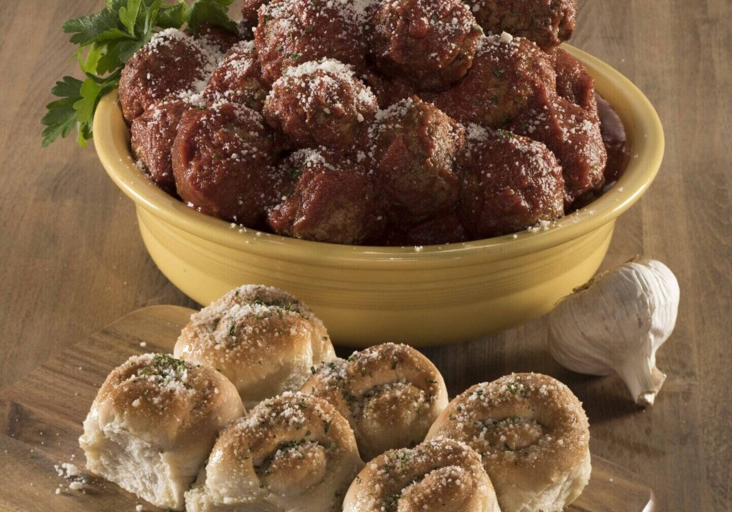 A bowl of meatballs and some rolls on the table