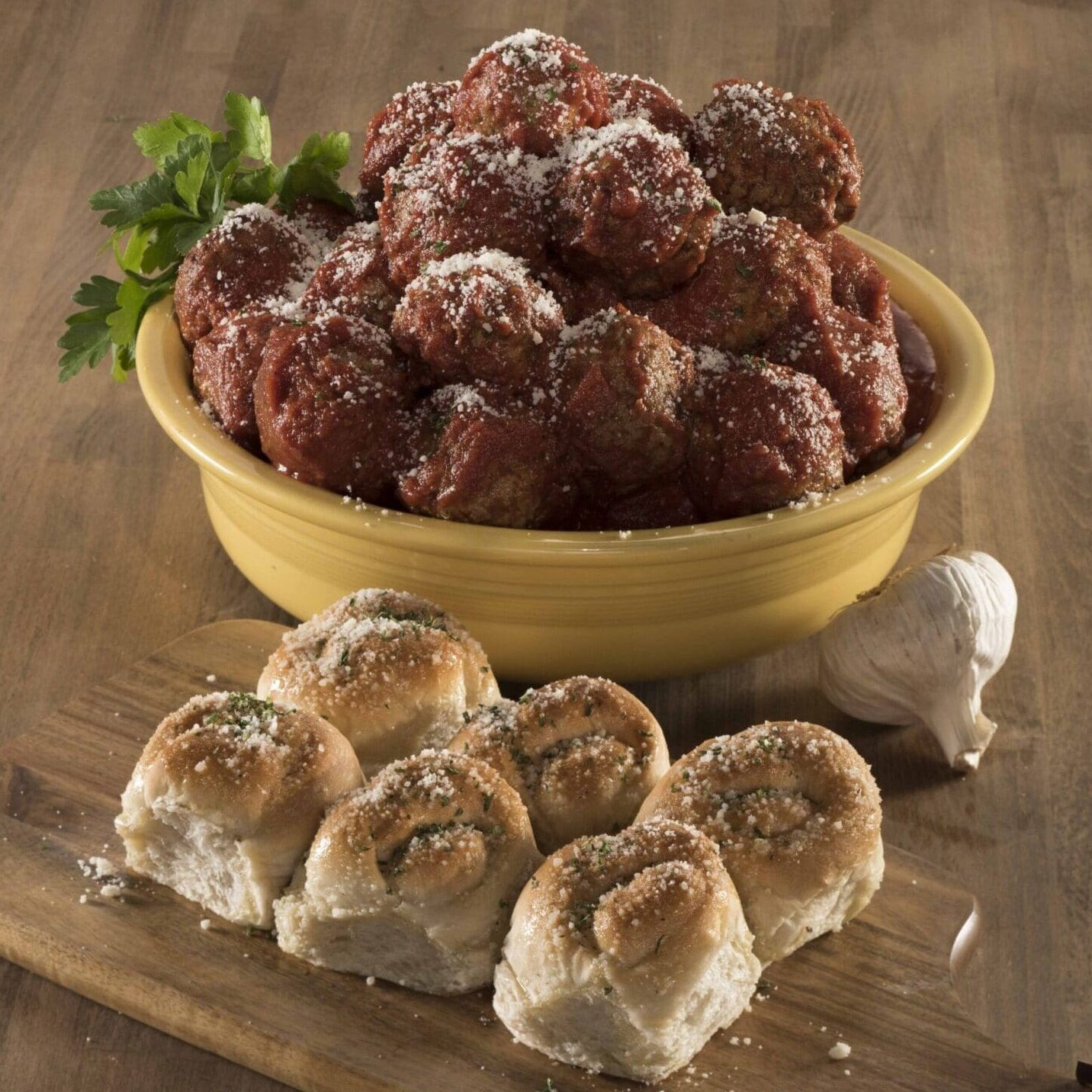 A bowl of meatballs and some rolls on the table